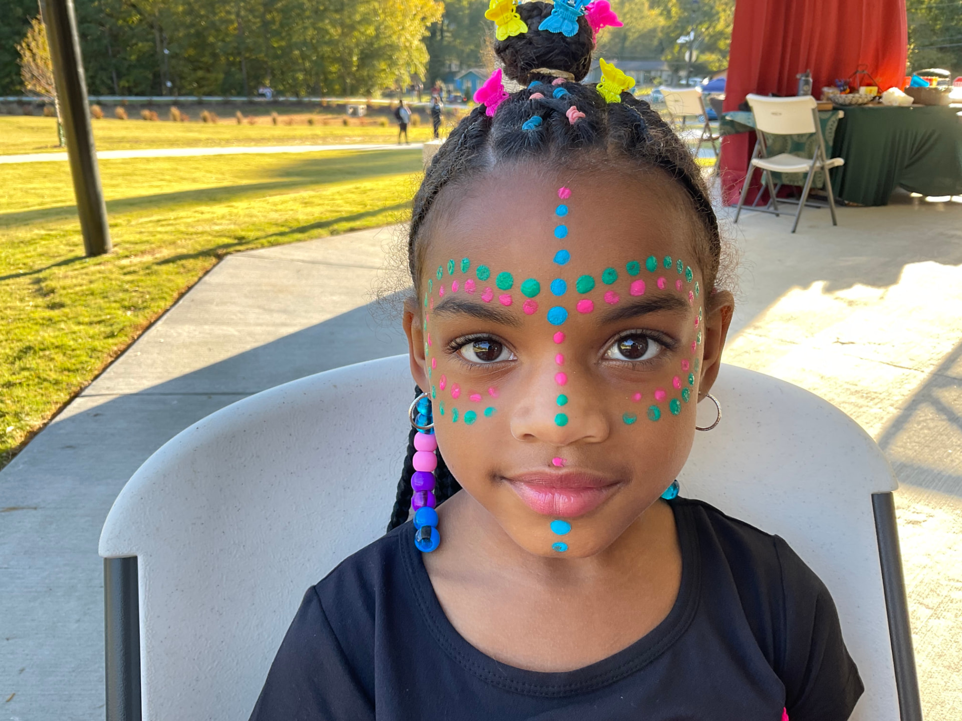 A child with colorful face painting at an outdoor community celebration